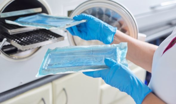 Female nurse doing sterilization of dental medical instruments in autoclave Female nurse doing sterilization of dental medical instruments in autoclave. Sterilization department at dental clinic